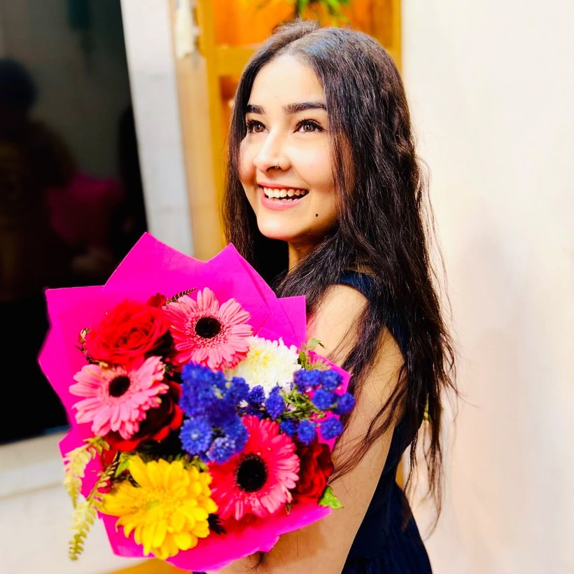 Avantika, founder of Alishaan Collection, smiling with a bouquet
